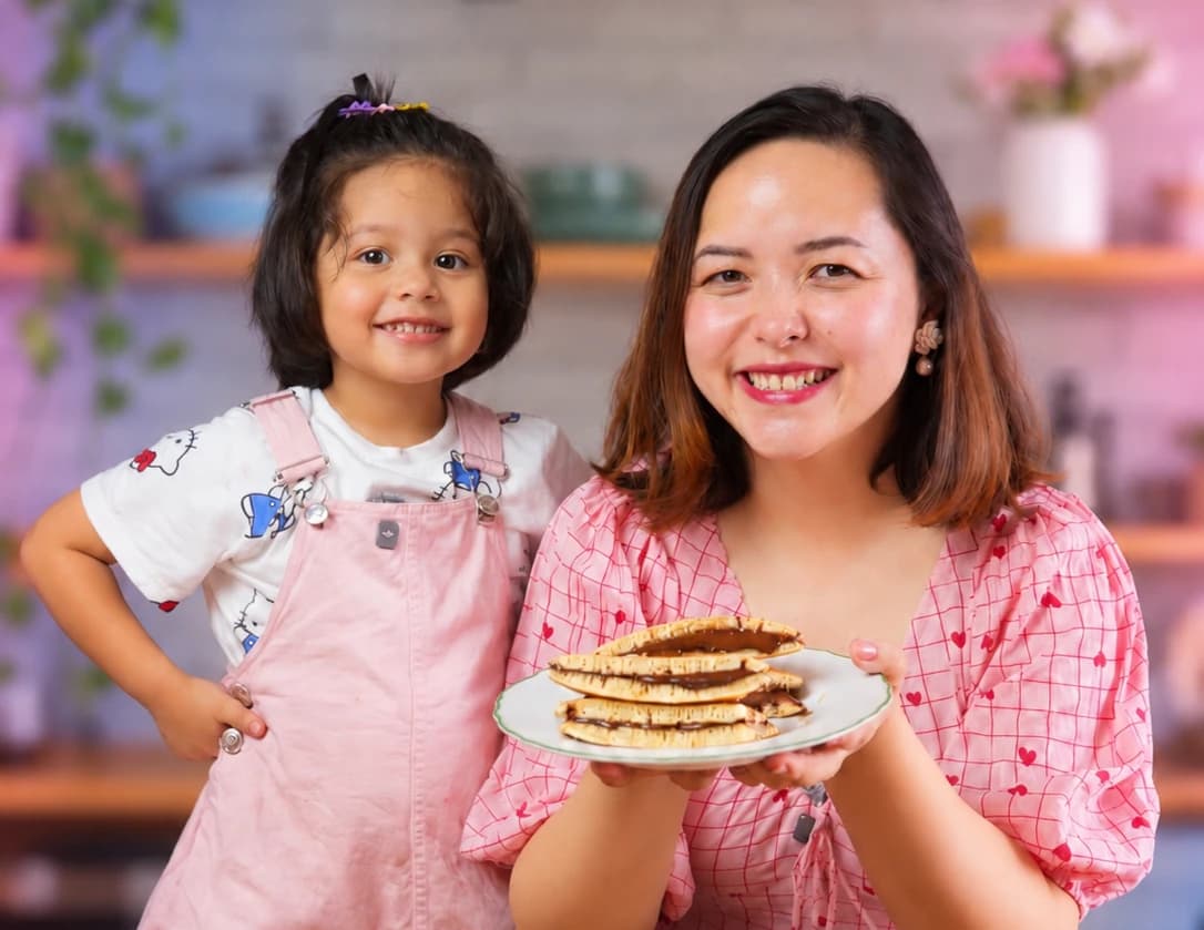 A mother and daughter holding up a plate of pancakes